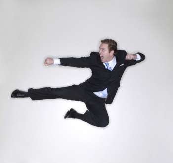 Businessman gives a karate kick in the air inside the office