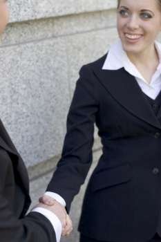 Businesswoman standing outside and giving a handshake