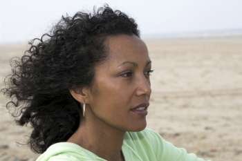 Beautiful black woman by the seaside enjoying the wind on her face