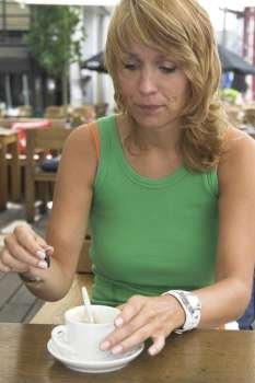 Pretty woman adding some sugar to her coffeecup