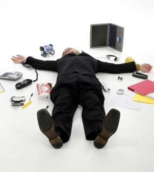 Business man laying on floor surrounded by office supplies.