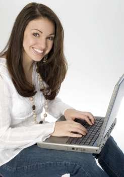Beautiful seventeen year old brunette with laptop computer. Lovely smile. Shot in studio.