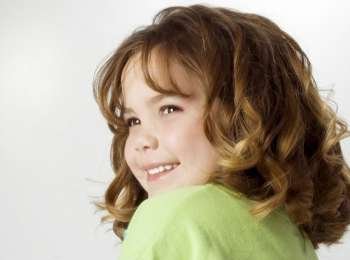 Beautiful five year old girl with big curls and huge smile.