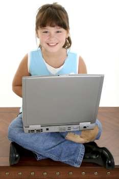 Beautiful Little Girl Working On Laptop Computer. Sitting crossed leg on a table. 