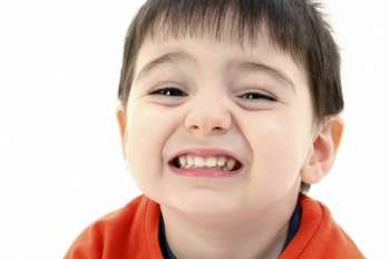 Close up of toddler boy smiling. Wearing orange casual shirt. 