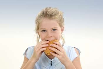 Beautiful Little Girl Eating a Cheeseburger over blue background.
