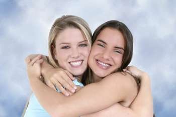 Two teen girls smiling and hugging. 