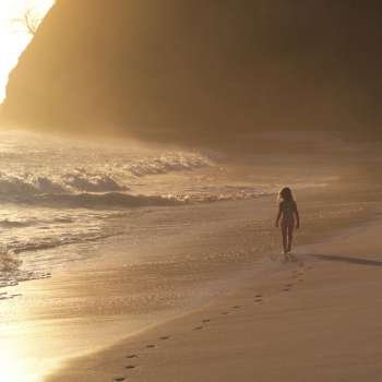 Girl walking on beach at sunset