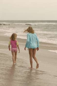 Caucasian girls walking down beach