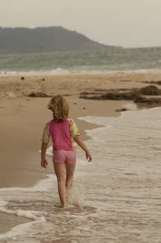 Caucasian girl walking down beach