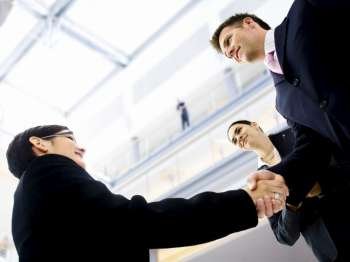 Business people shaking hands in the entrance hall of the office building. Selective focus is placed on the hands.