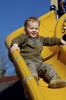 Young boy is playing outdoor and enjoys the speed on the slide-way.