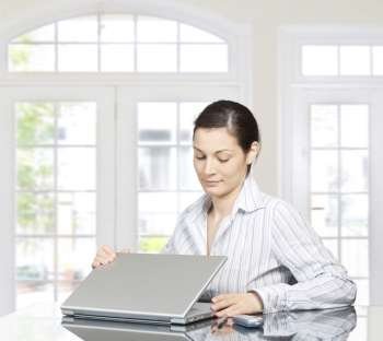 Young woman opens laptop computer. There is morning at home in a light and clean home interior dominated by white and soft tones.