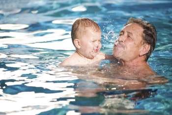 Grandfather and grandson playing together in the pool. Outdoor, summer.