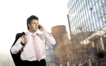 Young businessman walks and talks on a mobile phone, outdoor portrait.