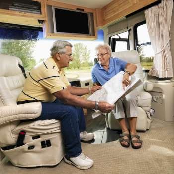 Senior couple sitting in RV looking at map and smiling.
