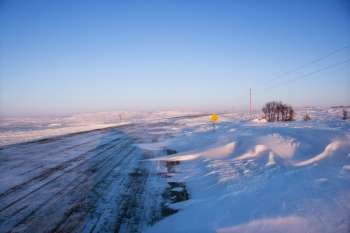 Ice covered road and snowy rural landscape.