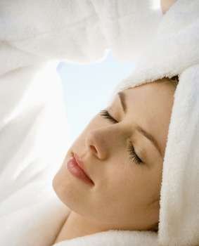 Caucasian mid-adult woman wearing towel on head with eyes closed relaxing.