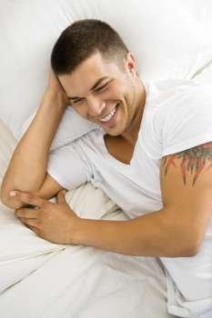 High angle view of handsome Caucasian mid adult man lying in bed smiling.