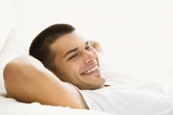 Handsome Caucasian mid adult man lying with hands behind head and smiling.