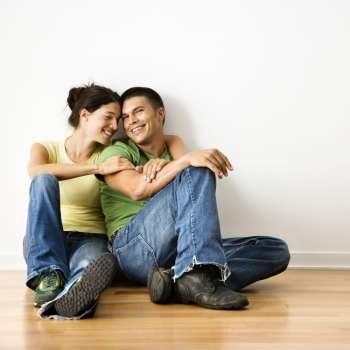 Smiling attractive couple sitting on floor in home.