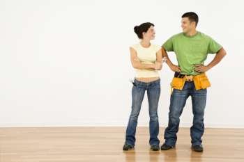 Couple with tools standing and smiling in home.