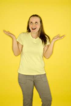 Young adult female Caucasian standing shrugging on yellow background.