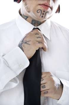 Caucasian mid-adult man with tattoos and piercings adjusting necktie.