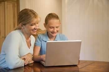 Caucasian mid-adult woman and pre-teen girl using laptop computer.