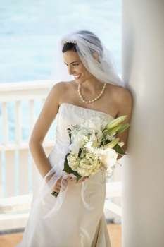 Caucasian mid-adult bride holding bouquet looking down.