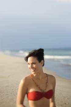 Caucasian mid-adult female smiling on beach in swimsuit.