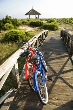 Image of red and blue bike leaning against railing of boardwalk.