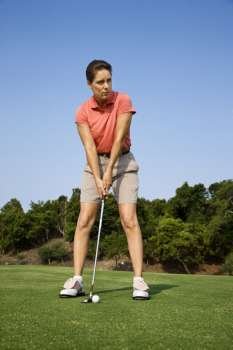 Caucasion mid-adult woman putting golf ball.