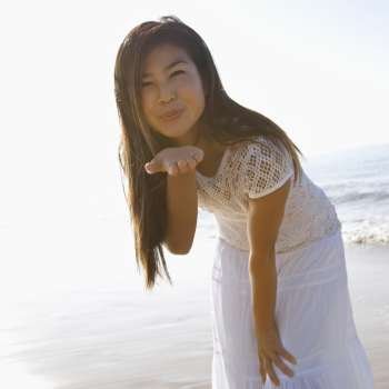 Young adult Asian female blowing a kiss toward viewer.