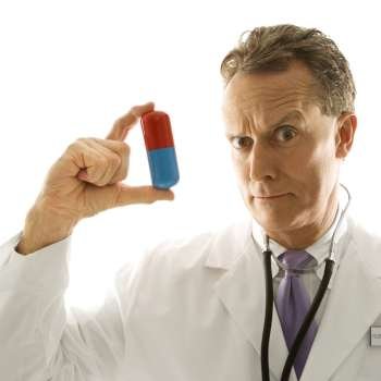 Mid-adult Caucasian male doctor holding an oversized medical pill.