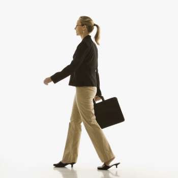 Mid-adult Caucasian businesswoman walking and carrying briefcase.