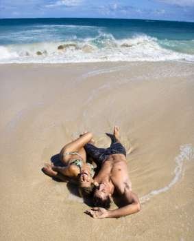 Attractive couple lying on beach smiling and laughing in Maui, Hawaii.