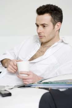 man relaxing on bed with hot drink in mug
