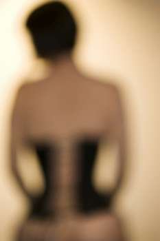 Blurred rear view shot of young Caucasian woman wearing corset.