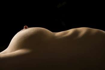 Side view of torso of nude Caucasian woman lying on back.