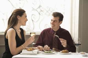 Mid adult Caucasian couple dining in restaurant and smiling.
