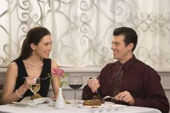 Mid adult Caucasian couple smiling eating in restaurant.
