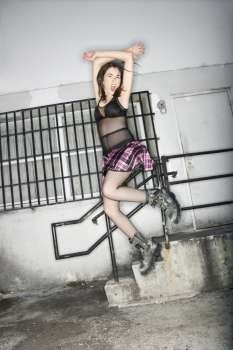 Portrait of pretty Caucasian young woman jumping in urban setting.