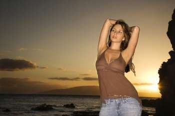 Portrait of sexy young Caucasian woman with arms behind head at scenic rocky coast in Maui Hawaii.
