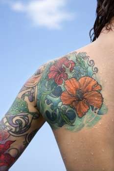 Close-up of Caucasian woman´s back and shoulder covered with floral tattoos.