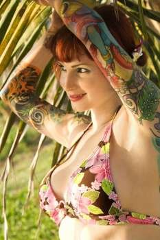 Portrait of sexy Caucasian redheaded woman in bikini with palm tree in Maui, Hawaii, USA.
