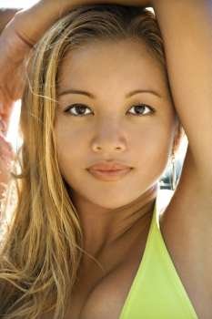 Beautiful young adult Asian Filipino female in swimsuit looking at viewer with arms raised in Maui Hawaii.
