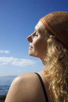 Profile of Caucasian mid-adult woman with wavy hair and head scarf at coast.