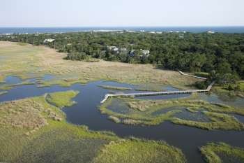 Aerial of marsh with dock and pier and houses in background in Bald Head Island, North Carolina.
