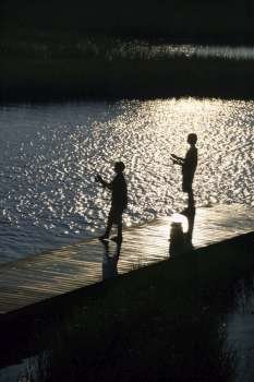 Birds eye view of two teenage boys fishing from dock at Bald Head Island, North Carolina.